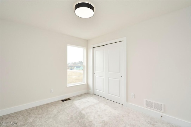 unfurnished bedroom with carpet flooring, baseboards, visible vents, and a closet