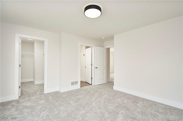 unfurnished bedroom with visible vents, a closet, carpet floors, baseboards, and a spacious closet
