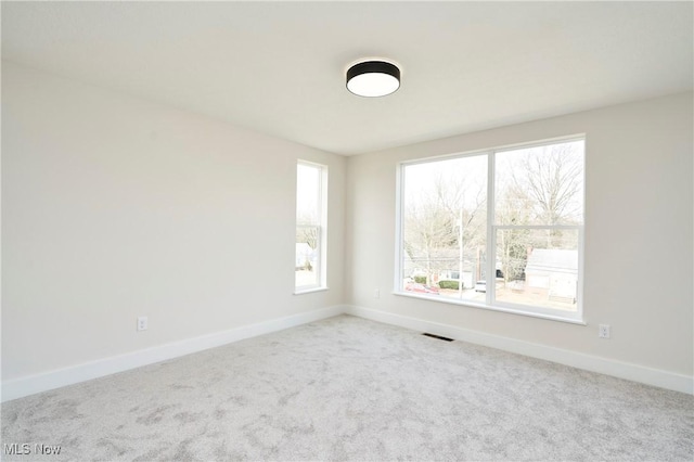 carpeted spare room featuring visible vents and baseboards