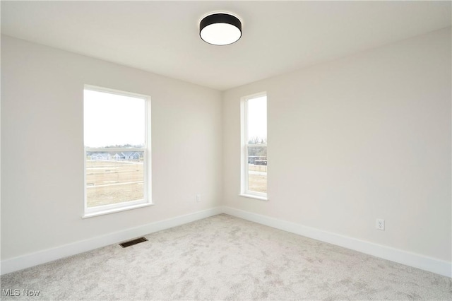 carpeted spare room with visible vents and baseboards