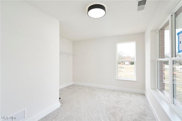 carpeted spare room featuring baseboards and visible vents