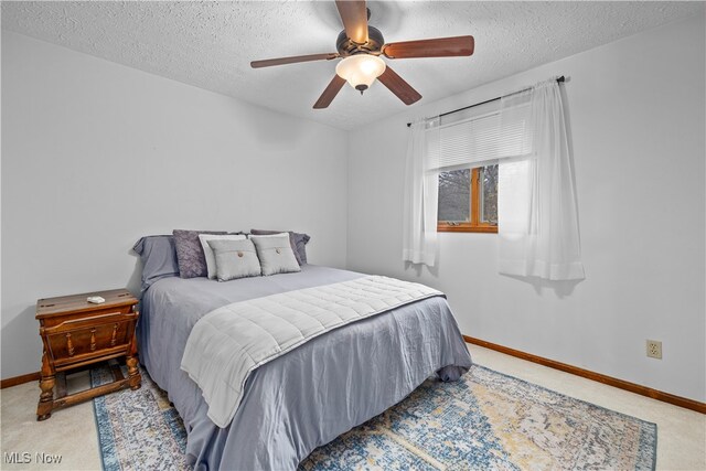 bedroom with ceiling fan, light colored carpet, and a textured ceiling