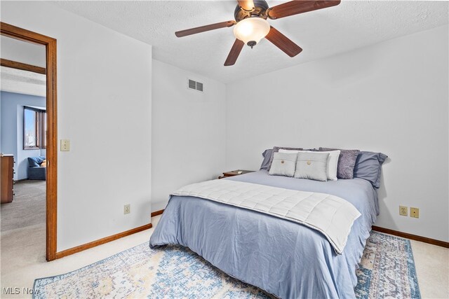 carpeted bedroom featuring ceiling fan and a textured ceiling