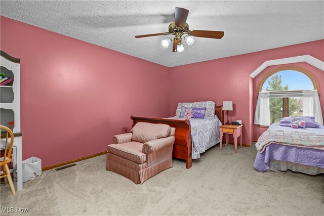 carpeted bedroom featuring ceiling fan and a textured ceiling