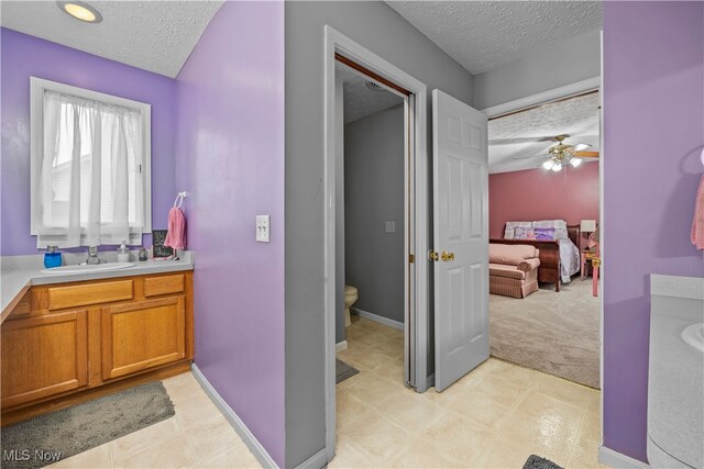 bathroom featuring vanity, a textured ceiling, toilet, and ceiling fan