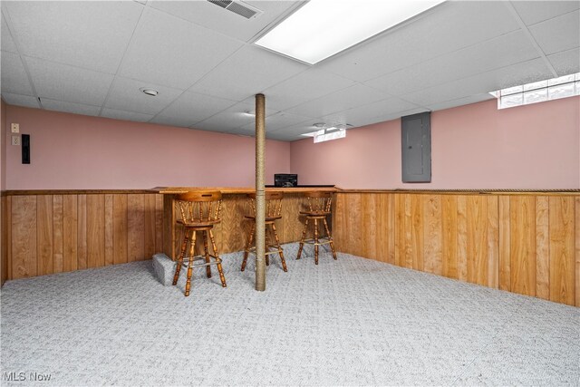 bar featuring carpet floors, electric panel, a drop ceiling, and wooden walls