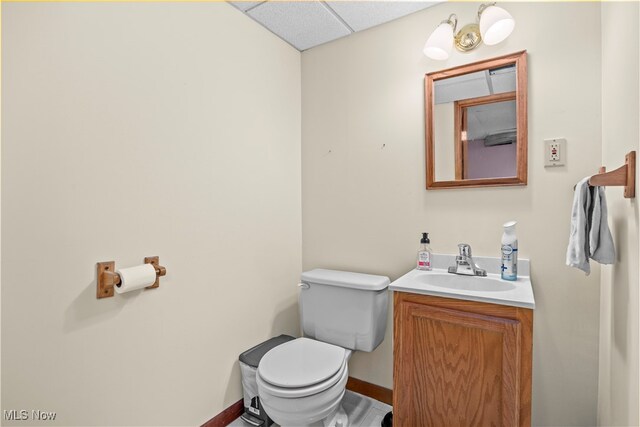 bathroom with a paneled ceiling, vanity, and toilet