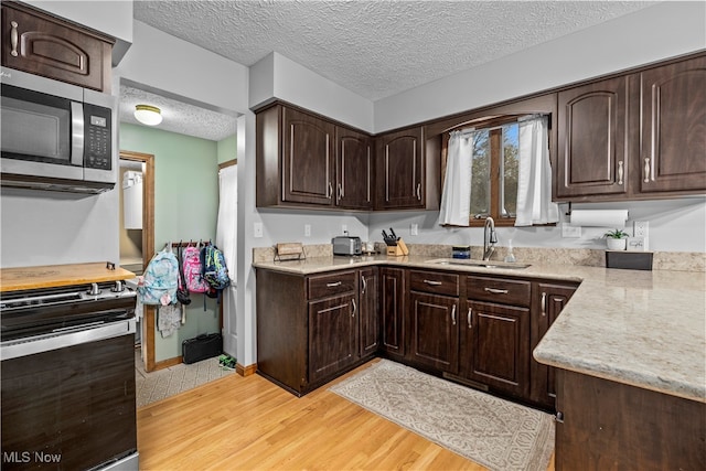 kitchen featuring dark brown cabinetry, light hardwood / wood-style floors, stainless steel appliances, and sink