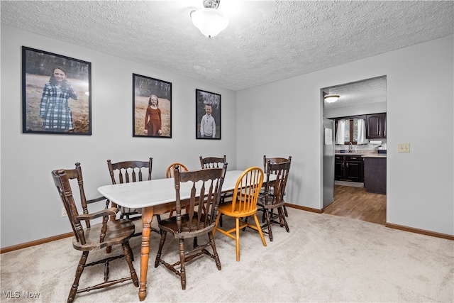 carpeted dining room featuring sink and a textured ceiling