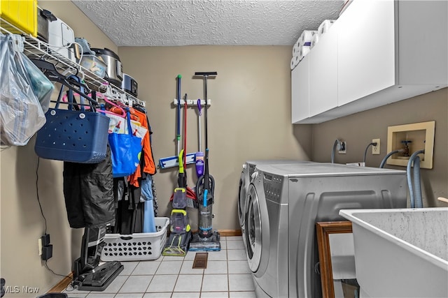 washroom featuring light tile patterned floors, cabinets, a textured ceiling, and independent washer and dryer