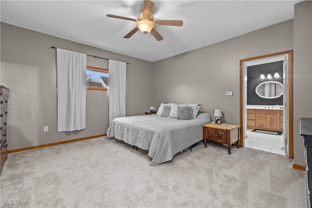 bedroom with ceiling fan, sink, light carpet, and connected bathroom