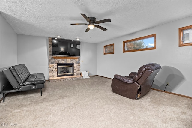 living room with carpet flooring, a stone fireplace, ceiling fan, and a textured ceiling