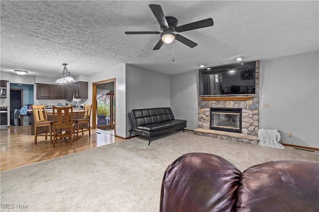 living room with light carpet, a textured ceiling, a fireplace, and ceiling fan