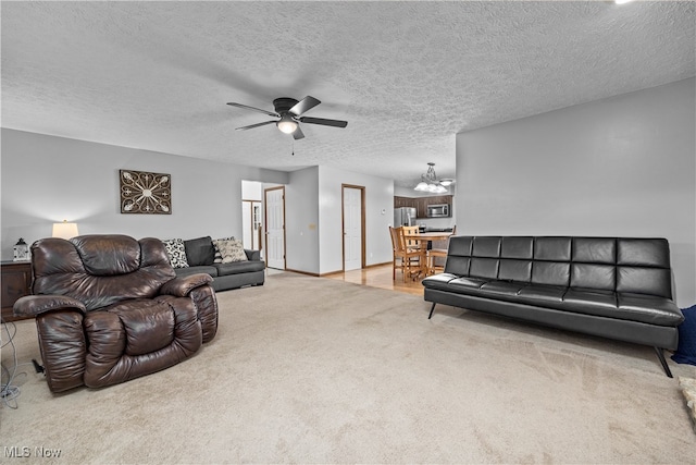 carpeted living room with ceiling fan with notable chandelier and a textured ceiling