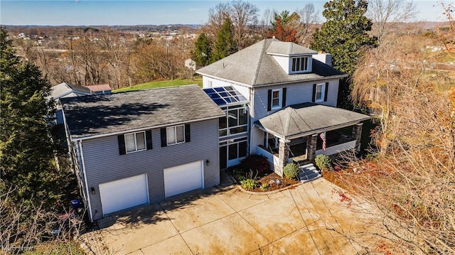 view of front of house with glass enclosure, a porch, and a garage