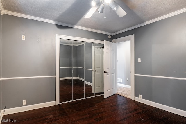 unfurnished bedroom featuring ceiling fan, dark hardwood / wood-style floors, a textured ceiling, a closet, and ornamental molding