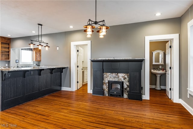 unfurnished living room with a tiled fireplace, dark hardwood / wood-style flooring, and sink