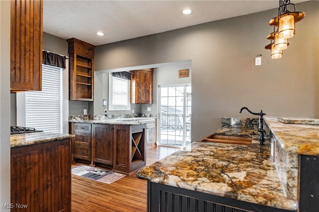 kitchen featuring light stone countertops, light wood-type flooring, decorative light fixtures, and a kitchen island