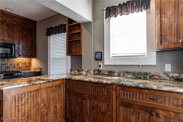 kitchen featuring dark stone counters, decorative backsplash, and black appliances