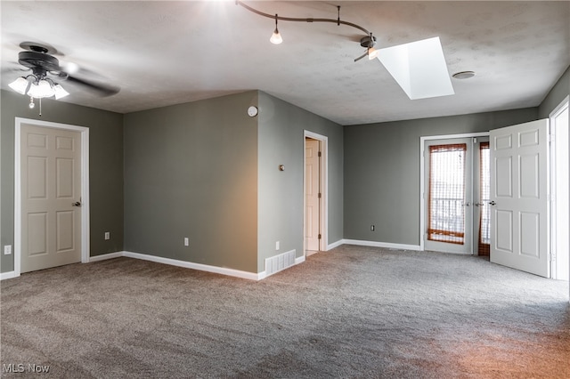 carpeted spare room featuring a skylight and ceiling fan