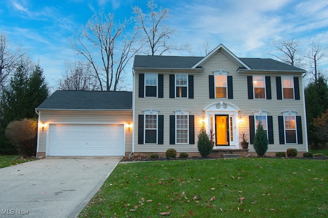 colonial house featuring a front yard and a garage