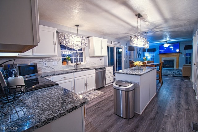 kitchen with white cabinets, decorative light fixtures, a center island, and dark wood-type flooring