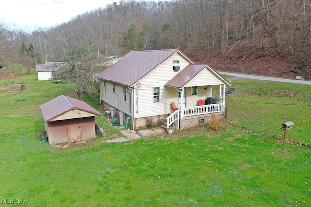 view of front of home with a porch, an outbuilding, and a front lawn