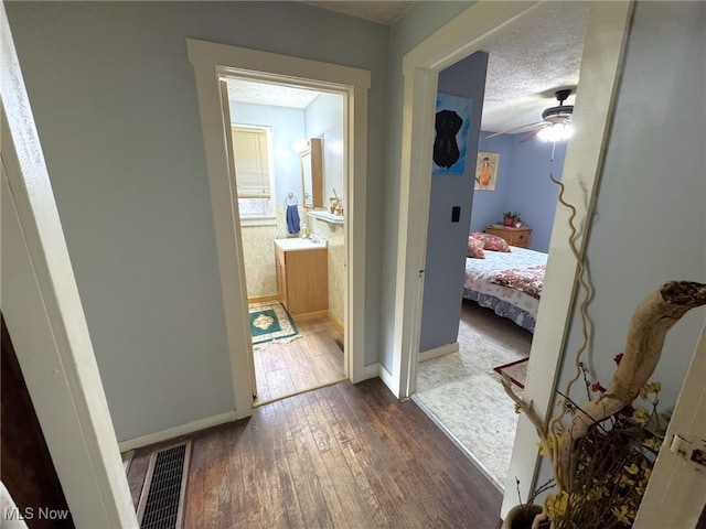 corridor featuring a textured ceiling and dark hardwood / wood-style floors