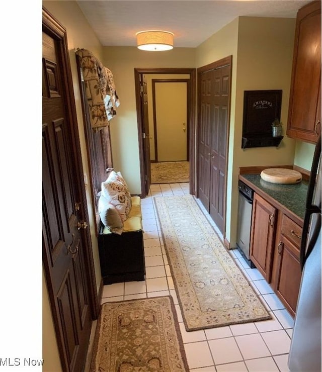 interior space with light tile patterned flooring and stainless steel dishwasher