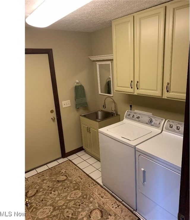 laundry room featuring sink, cabinets, washing machine and dryer, a textured ceiling, and light tile patterned floors