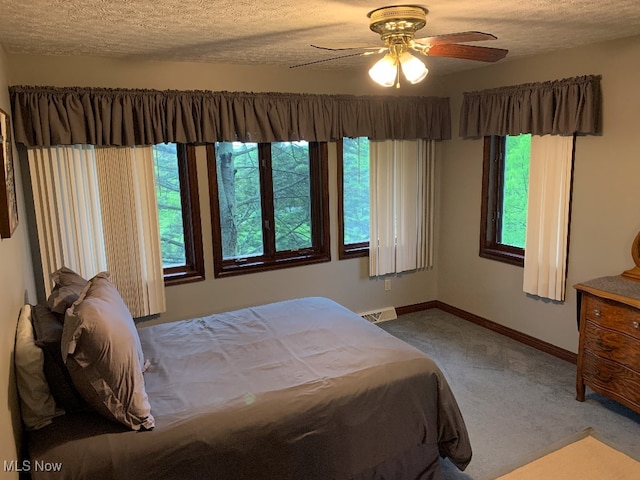 bedroom with carpet flooring, ceiling fan, and a textured ceiling