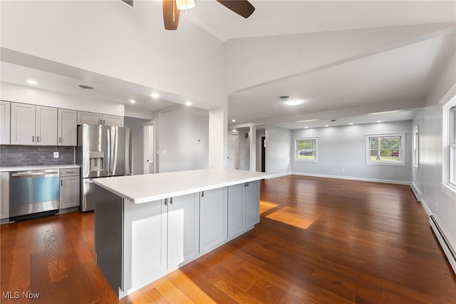 kitchen with gray cabinetry, stainless steel appliances, vaulted ceiling, hardwood / wood-style flooring, and a center island