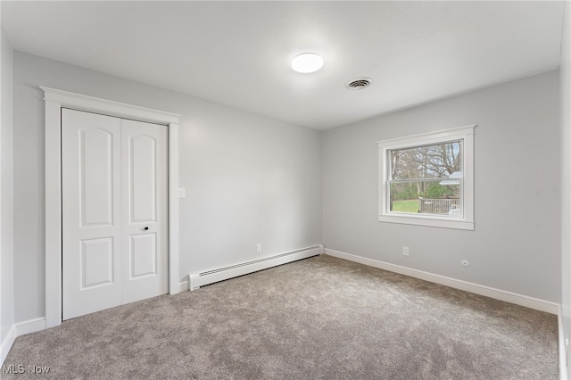 unfurnished bedroom with carpet flooring, a closet, and a baseboard heating unit