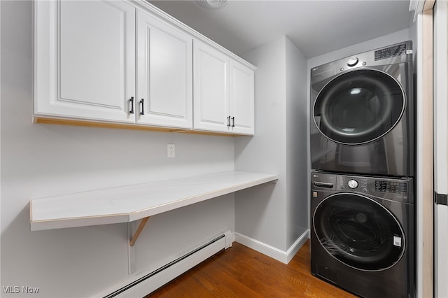 washroom featuring cabinets, stacked washer and dryer, baseboard heating, and dark wood-type flooring