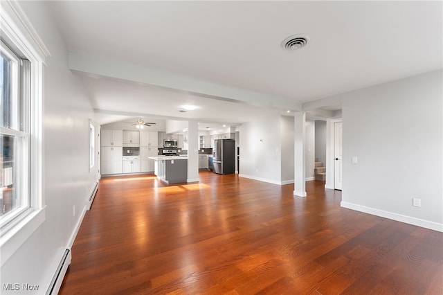 unfurnished living room featuring ceiling fan, baseboard heating, and dark wood-type flooring