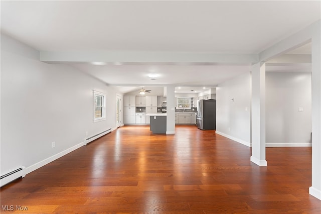 unfurnished living room with dark hardwood / wood-style floors, a wealth of natural light, and a baseboard radiator