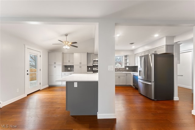 kitchen featuring decorative backsplash, appliances with stainless steel finishes, ceiling fan, dark hardwood / wood-style floors, and lofted ceiling