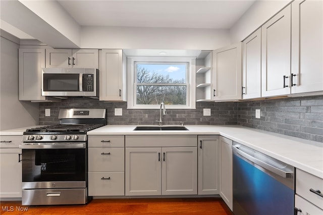 kitchen with decorative backsplash, appliances with stainless steel finishes, wood-type flooring, and sink