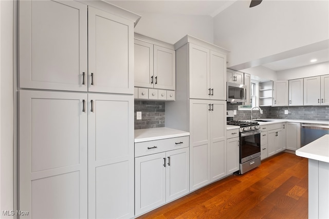 kitchen with backsplash, sink, appliances with stainless steel finishes, dark hardwood / wood-style flooring, and white cabinetry