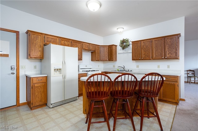 kitchen featuring sink, a kitchen breakfast bar, light colored carpet, white appliances, and a kitchen island