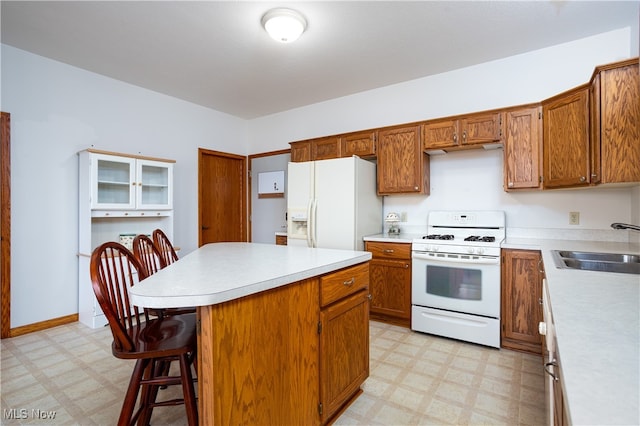 kitchen featuring a breakfast bar, white appliances, a kitchen island, and sink