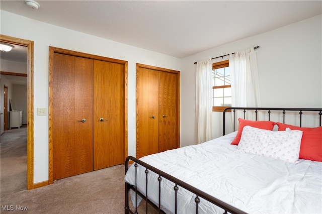 bedroom featuring two closets and light colored carpet