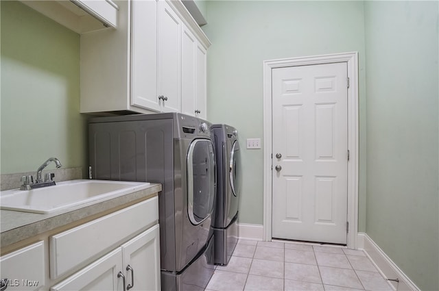 laundry area featuring sink, washer and clothes dryer, cabinets, and light tile patterned flooring