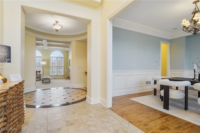 entrance foyer with light hardwood / wood-style flooring, crown molding, and a chandelier