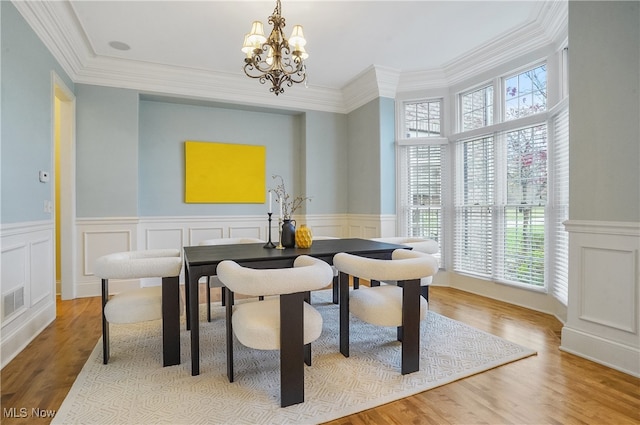 dining area with crown molding, a notable chandelier, and light wood-type flooring