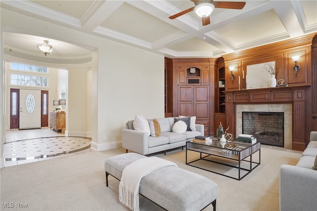 living room with coffered ceiling, a high end fireplace, ornamental molding, and beamed ceiling