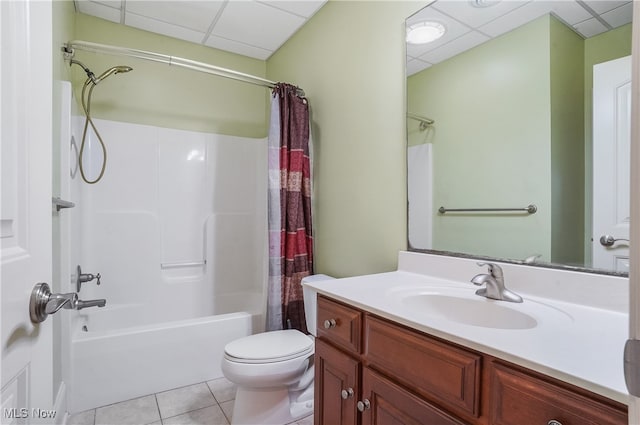 full bathroom featuring tile patterned floors, toilet, vanity, shower / bath combo with shower curtain, and a drop ceiling