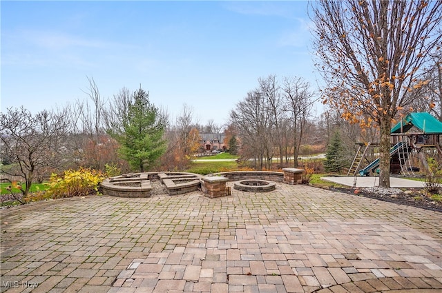 view of patio with a playground and an outdoor fire pit