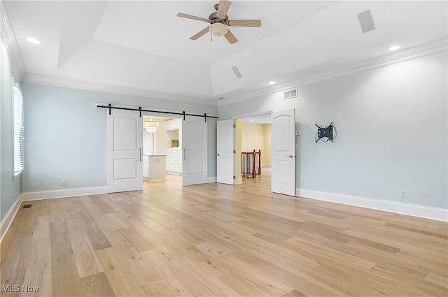 spare room with crown molding, a tray ceiling, and a barn door