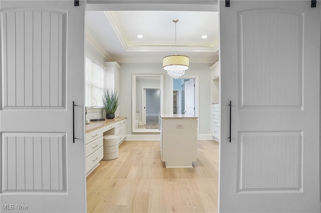 kitchen featuring white cabinetry, ornamental molding, a barn door, and hanging light fixtures